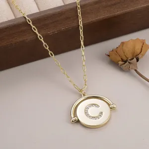 Gros plan du collier doré rotatif avec pendentif rond et lettre C en strass brillant