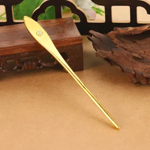 Close-up detail of an elegant gold Chinese style hairpin with a white jade-like bead