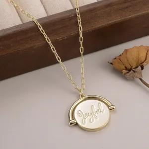 Une vue détaillée du collier avec pendentif rond en or et écriture Joyful gravée.