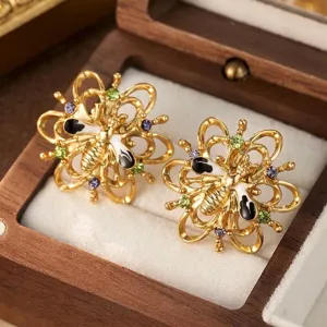 Detailed macro shot of vintage-style gold bee earrings with colorful enamel and stones