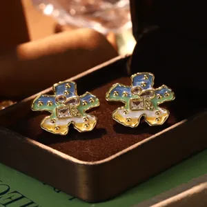 Detailed macro view of colorful oil painting style enamel flower earrings in a box