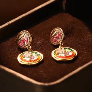 Detailed macro view of vintage flower oil painting enamel earrings in a jewelry box