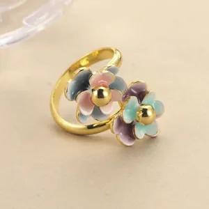 Detailed view of an adjustable gold-plated ring featuring two colorful enamel flowers