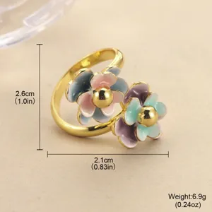 Macro detail of a golden ring featuring two colorful gradient enamel flowers.