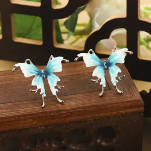 Vue détaillée de boucles d'oreilles papillon en émail bleu et blanc sur une boîte.