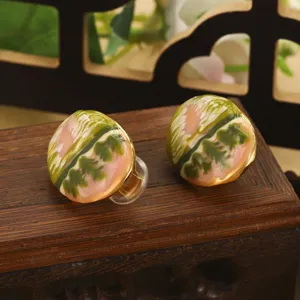 Gros plan de boucles d'oreilles clips émail sur base en bois