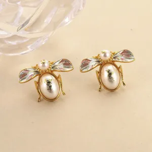 Detailed view of handmade vintage enamel bee earrings with elegant gold leaf pearls