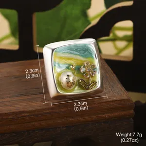 Vue macro d'une boucle d'oreille fleur en émail avec perle naturelle et accents dorés