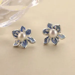 Detailed macro shot of blue enamel gradient flower stud earrings with a central pearl