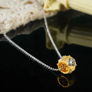 Macro detail of a vintage court style gold and silver textured necklace pendant charm.