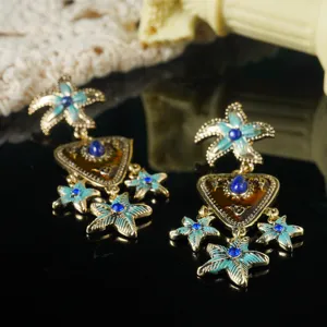 Detail van vintage emaille zeester oorbellen met blauwe strass steentjes en goud finish