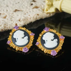 Gedetailleerde weergave van vintage cameo oorbellen met gouden montuur en paarse rozen.
