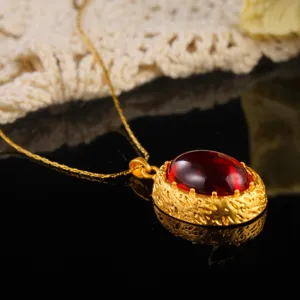 Macro detail of a vintage court style necklace with a large red oval gemstone.