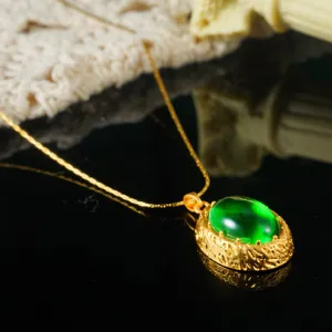 Detail shot of vintage gold necklace with oval green stone on reflective surface