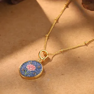 Close-up of vintage flower pendant necklace with blue enamel and pink floral pattern