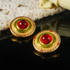 Macro view of vintage palace style gold stud earrings with red stone and green enamel