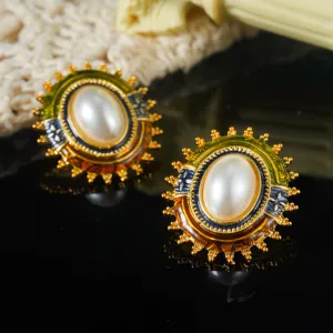 Close-up van vintage Franse emaille oorbellen met witte parels en gouden accenten