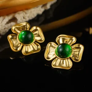 Macro detail shot of vintage gold flower earrings featuring elegant emerald green centers.