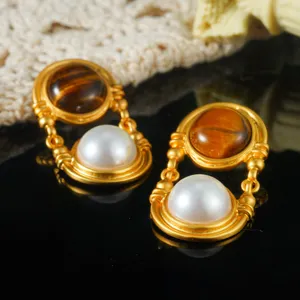 Macrodetail van vintage gouden oorbellen met tijgeroog en witte parels voor vrouwen