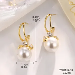 Detaillierte Ansicht eleganter goldener Perlenohrringe mit glitzerndem Bogen