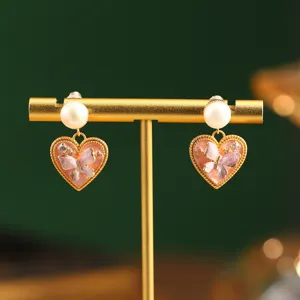 Detailed view of vintage Monet style heart earrings with pearl and butterfly motif.
