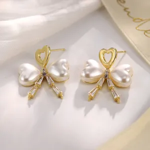 Detailaufnahme eleganter goldener Schleifenohrringe mit weißen Perlen und Kristallen