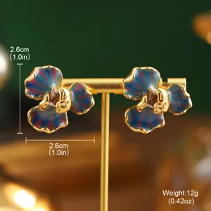 Gros plan de boucles d'oreilles fleurs en émail avec motifs de peinture à l'huile