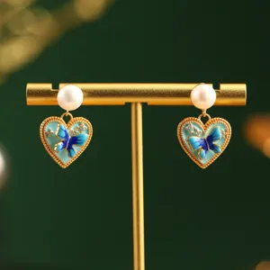 Detailed view of vintage heart-shaped earrings featuring blue butterflies and natural pearls