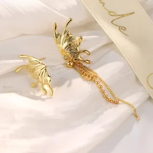Nahaufnahme von goldenen Schmetterlingsohrringen mit eleganten langen Perlenquasten.