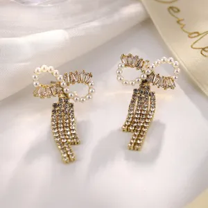 Nahaufnahme von eleganten goldenen Perlen-Ohrringen mit glänzenden Kristallquasten