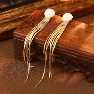 Detailansicht eleganter Perlenohrstecker mit langen goldenen Quastenketten.