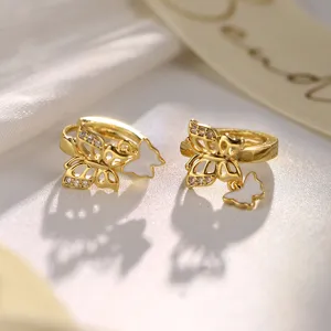 Elegante goldene Schmetterlings-Creolen mit funkelnden Kristallen und weißen Anhängern.