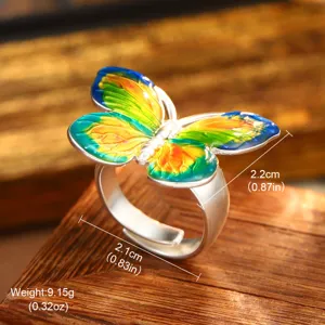 Detailed view of a vintage butterfly ring with colorful enamel on a wooden surface