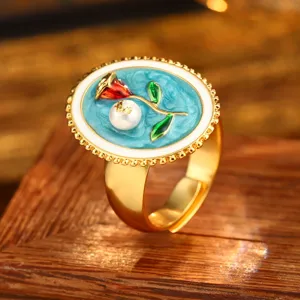 Macro detail of a vintage baroque enamel ring featuring a red rose and pearl accent
