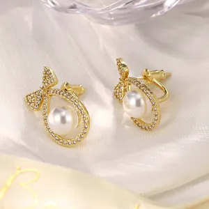 Nahaufnahme eleganter goldener Schleifenohrringe mit glänzenden Perlen und Strasssteinen.