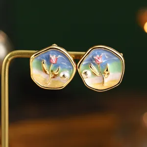Gros plan de boucles d'oreilles émaillées artistiques avec perle naturelle et fleurs