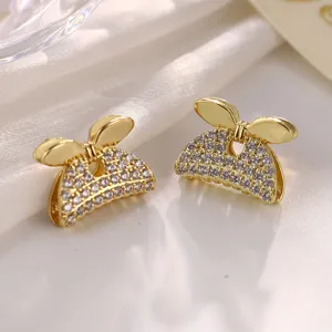 Detailaufnahme der funkelnden mit Strass besetzten goldenen Schleifenohrstecker.