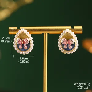 Macro view of Monet garden style oil painting earrings with pearl trim and bow design