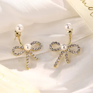 Detailansicht eleganter goldener Schleifenohrringe mit Kristallen und Perlenbesatz