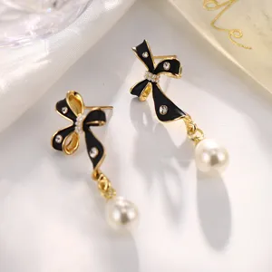Detaillierte Makroansicht eleganter schwarzer Emaille-Schleifenohrringe mit einer Tropfenperle