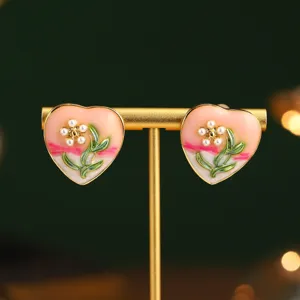 Gros plan de boucles d'oreilles cœur vintage avec fleurs en perles et émail vert