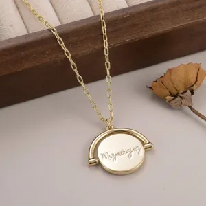 Gros plan sur un collier doré avec pendentif rotatif et texte gravé en cursive