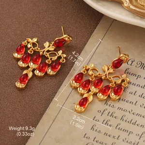 Vintage gold drop earrings with red stones and dimensional markers in detail view.