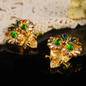 Close-up of vintage enamel owl earrings with green eyes and crystal accents.