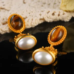 Macro detail of vintage court style drop earrings with pearl and faux tiger eye stone