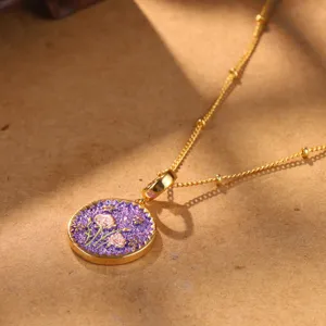 Detail view of a retro floral pendant necklace with purple enamel on a golden chain.