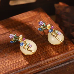 Dettaglio di orecchini orientali vintage con fiori smaltati e pietra a goccia bianca
