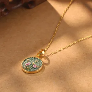 Macro view of vintage Chinese style gold pendant with green enamel and pink flowers