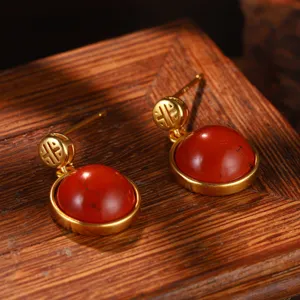 Macro dettagliata di orecchini dorati in stile cinese con pietre di agata rossa.