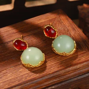 Dettaglio ravvicinato di orecchini stile cinese con finta giada verde e gemme rosse